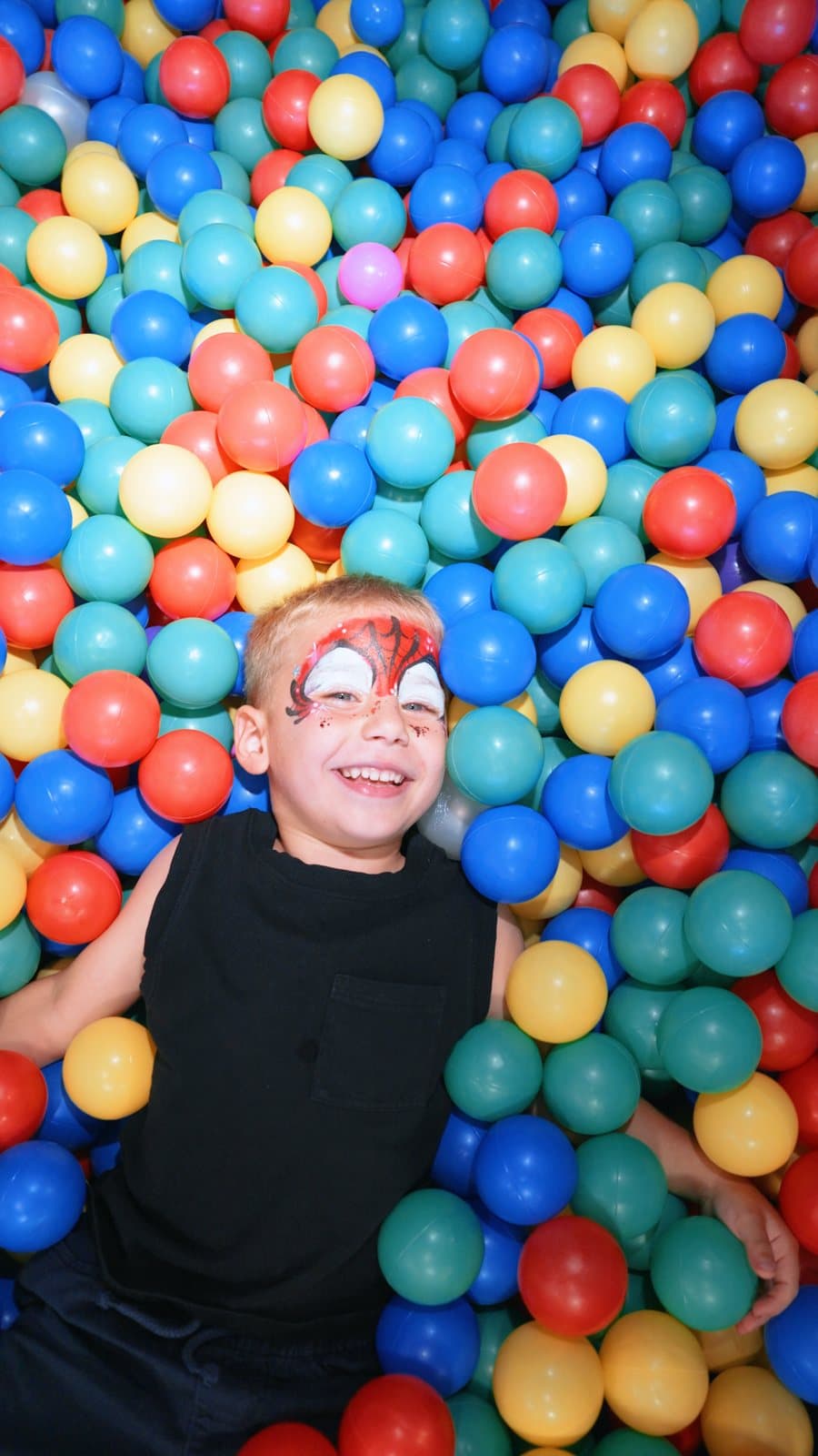 A boy with face paint in the ball pit