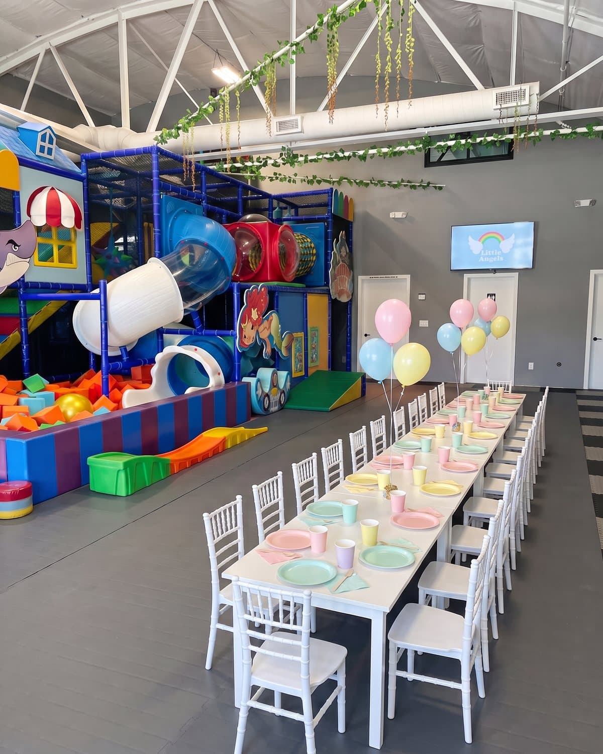 The party room set for a party, with the climbing structure and slides behind the table